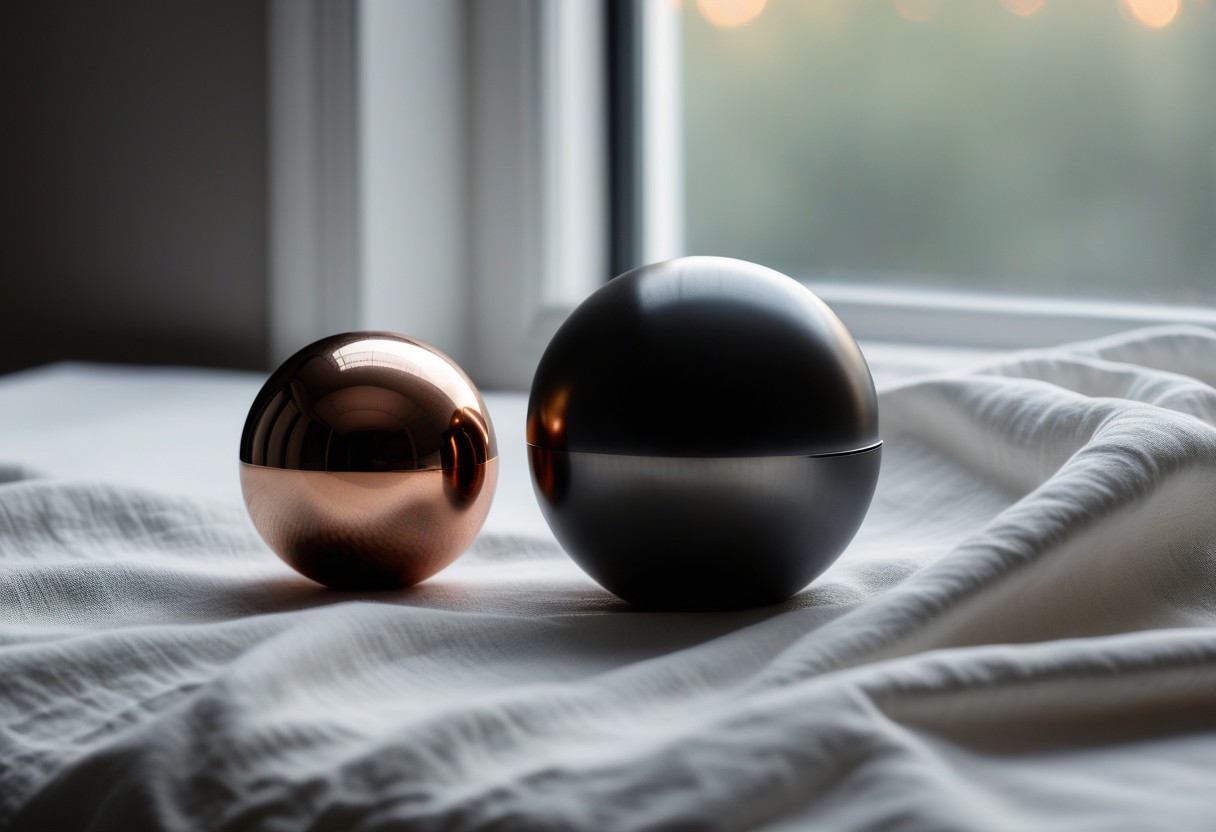 Reflective steel sphere and translucent silicone cube arranged on white fabric with diffused natural lighting.